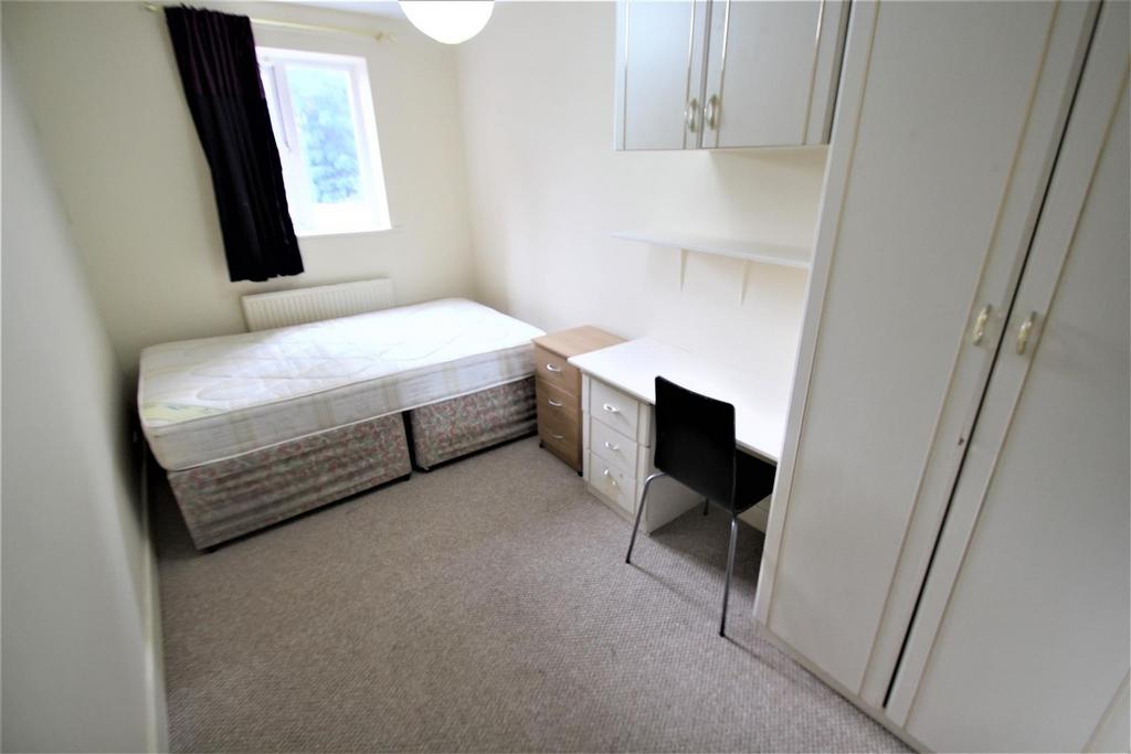 A compact bedroom featuring a single bed with a...