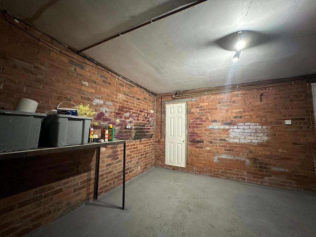 Red-brick walled storage room with a concrete f...