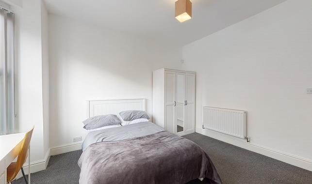 Bright, simply styled double bedroom with a com...