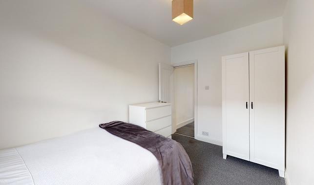 Bright, simply furnished bedroom with a comfort...