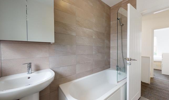 Modern bathroom with a white bathtub, glass sho...