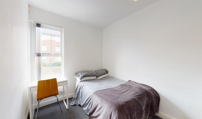 Bright, simply furnished bedroom with a single ...