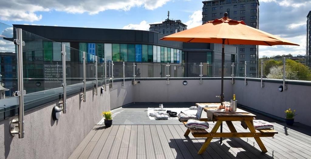 Sunny rooftop terrace with glass balustrades, w...
