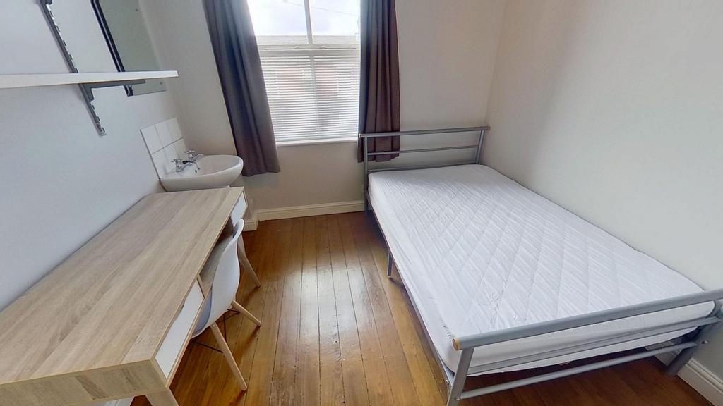 A well-lit, tidy bedroom featuring a single bed...