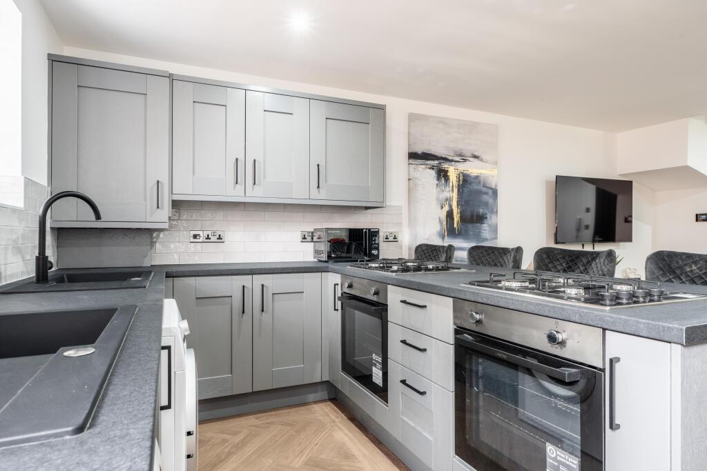 A modern, well-lit kitchen featuring sleek grey...