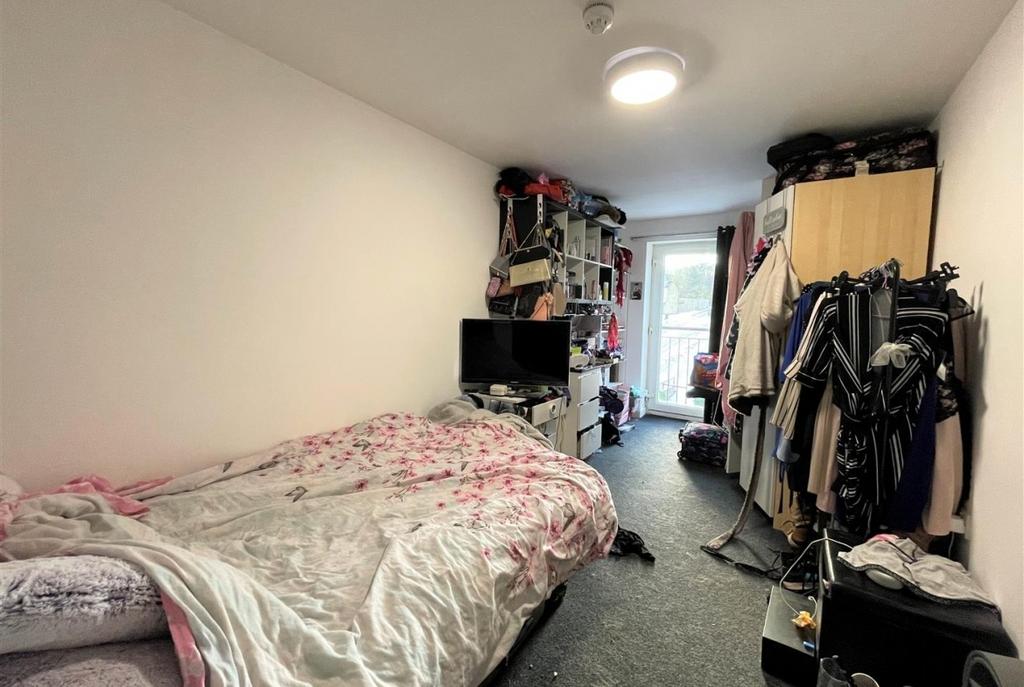 Bright, long bedroom with a comfy bed, built sh...