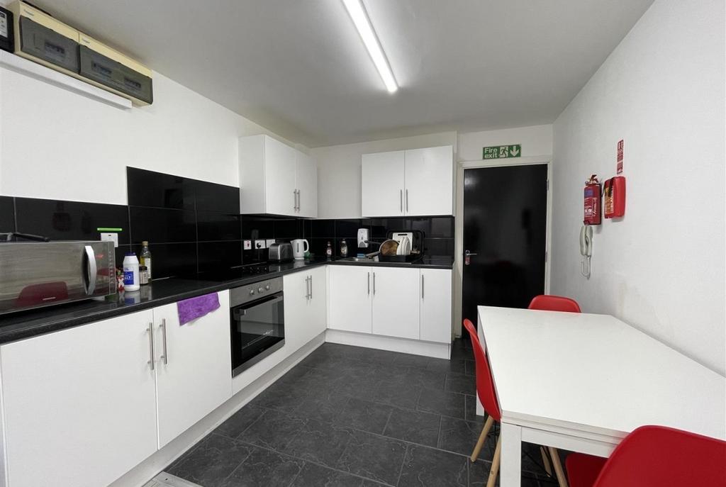 Modern shared kitchen with white cabinetry, bla...