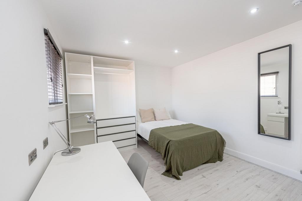 A clean, well-lit bedroom featuring a comfortab...