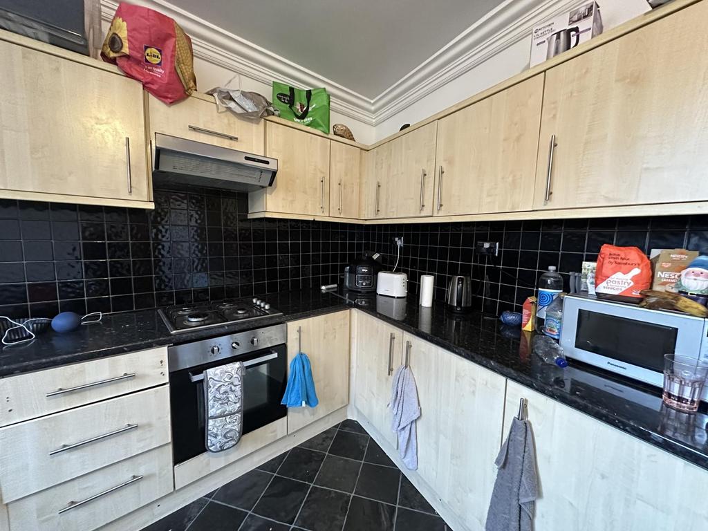 A modern kitchen with black tiled backsplash an...