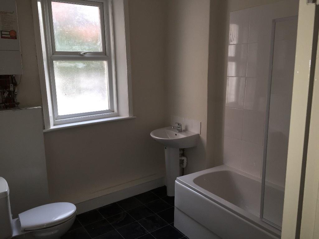 Bright, clean bathroom with a bathtub and showe...