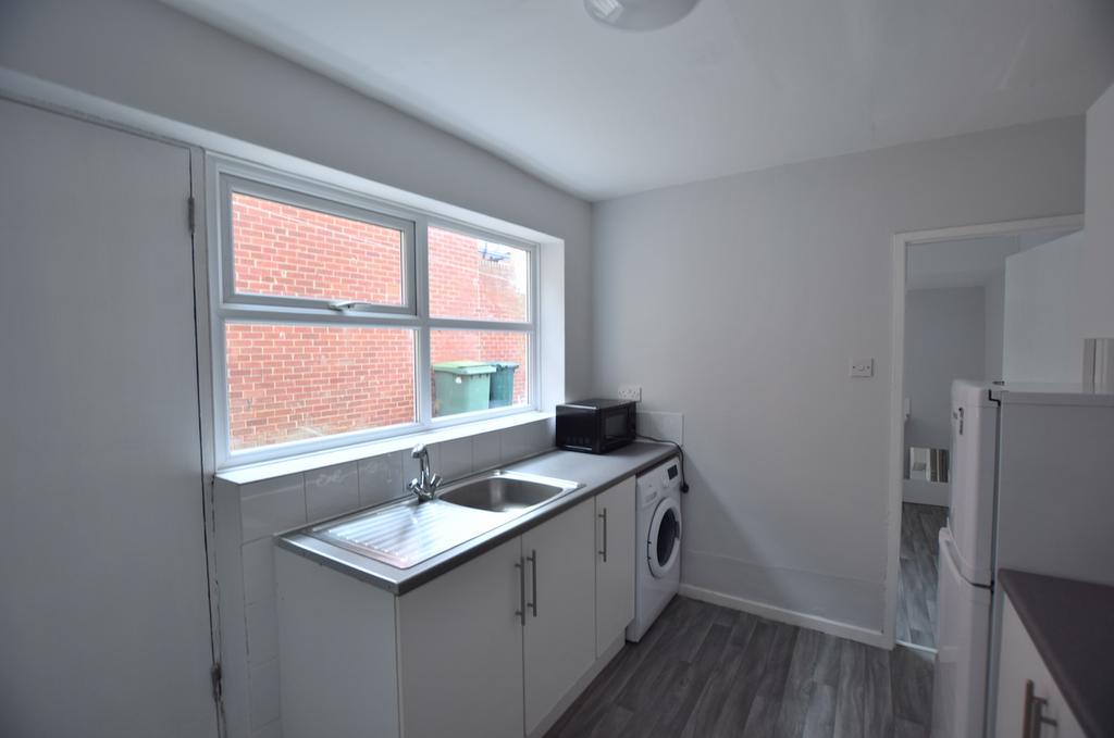 Bright, modern galley kitchen with a large wind...