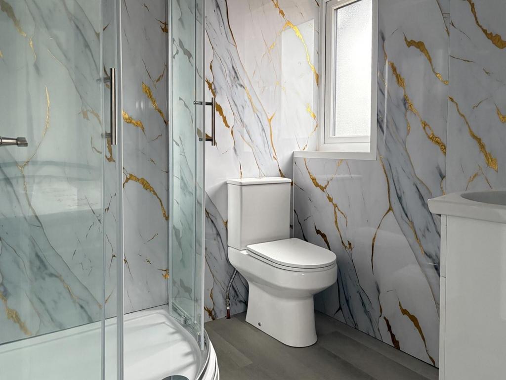 Modern bathroom with marble-effect tiled walls,...