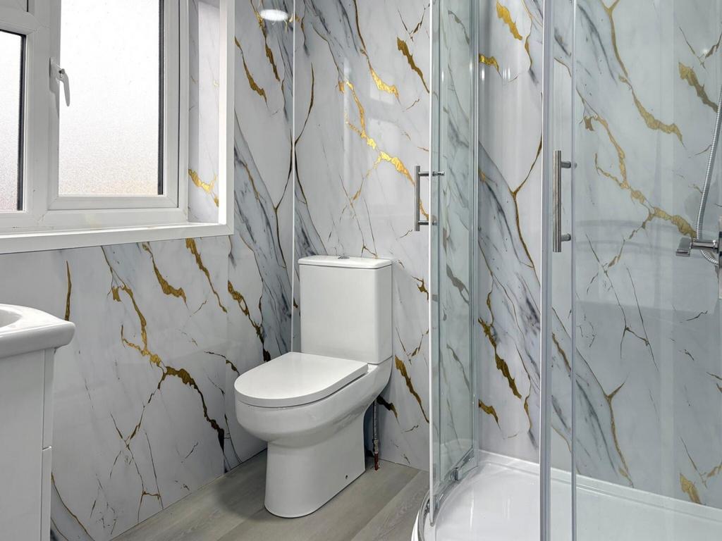 Modern bathroom with marble-effect wall tiles, ...