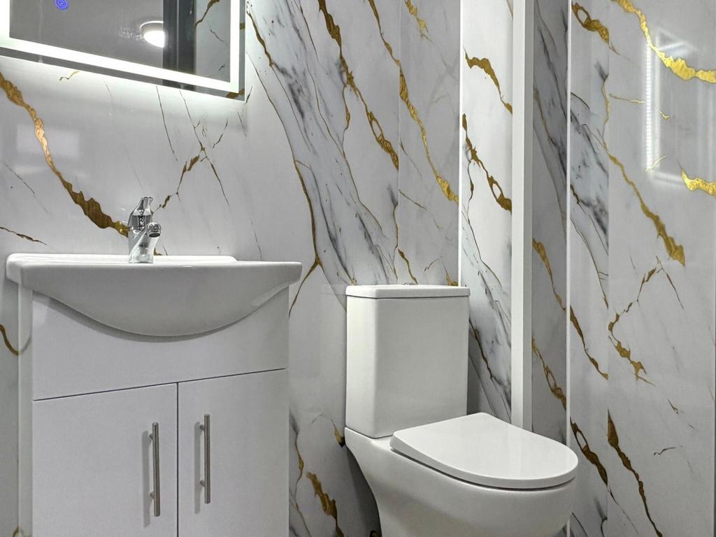 Bright modern bathroom with marble-effect wall ...
