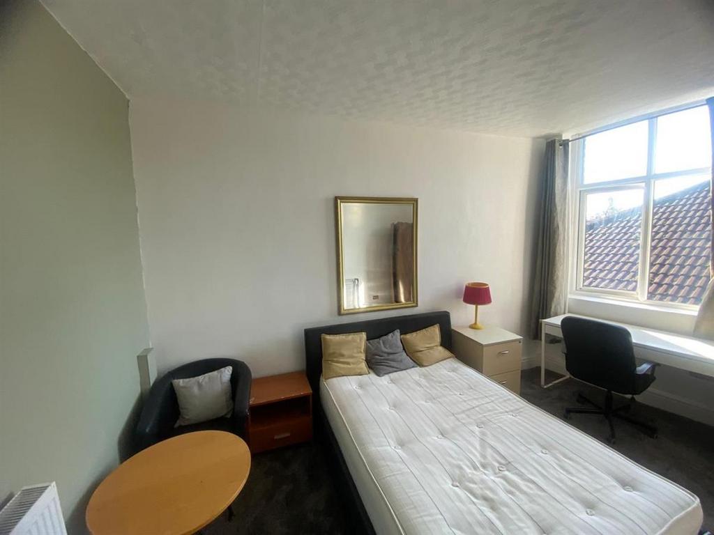 Bright single bedroom with a large window, fitt...