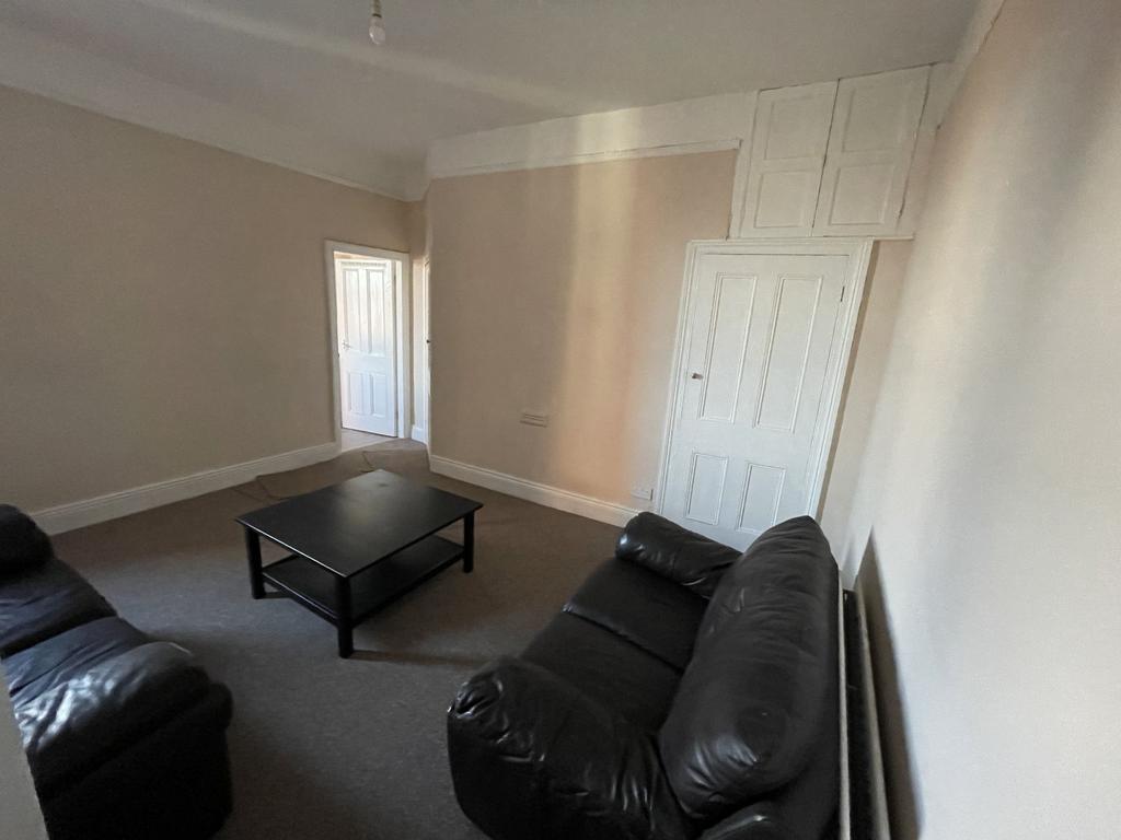 Bright neutral living room with two black leath...