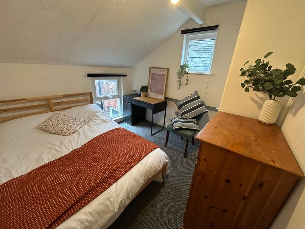 Cozy bedroom featuring a double bed with a wood...