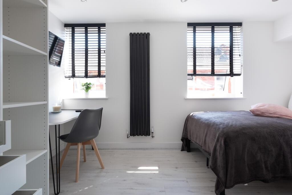 Bright and minimalist bedroom featuring a comfo...