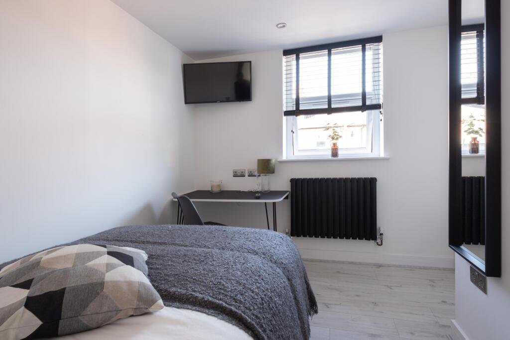 A tidy and modern single bedroom with a comfort...
