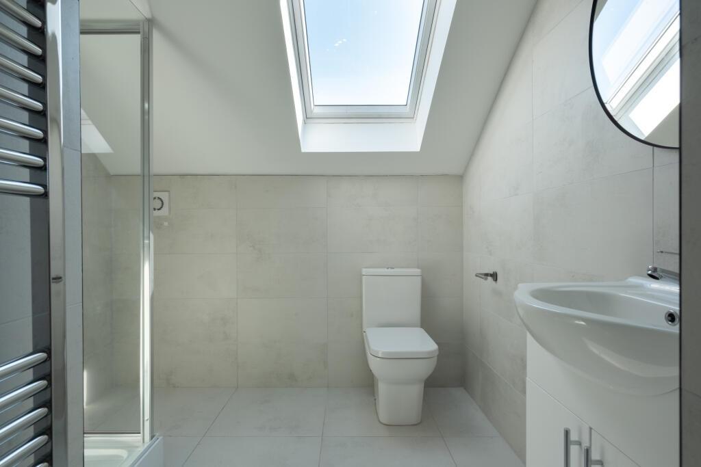 A bright, modern bathroom featuring a clean whi...