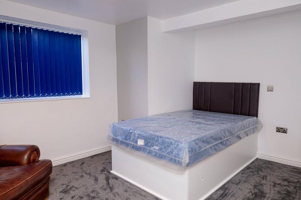 A simple and clean student bedroom with a bed w...