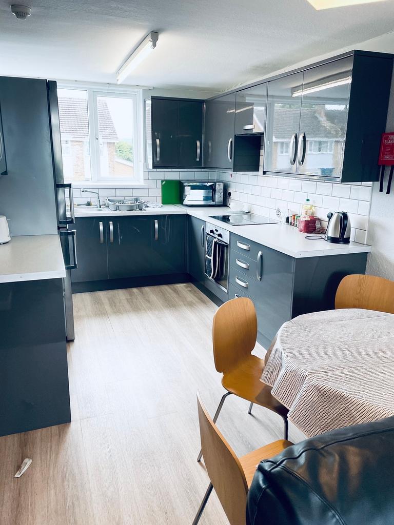 Bright modern kitchen with grey gloss cabinets,...