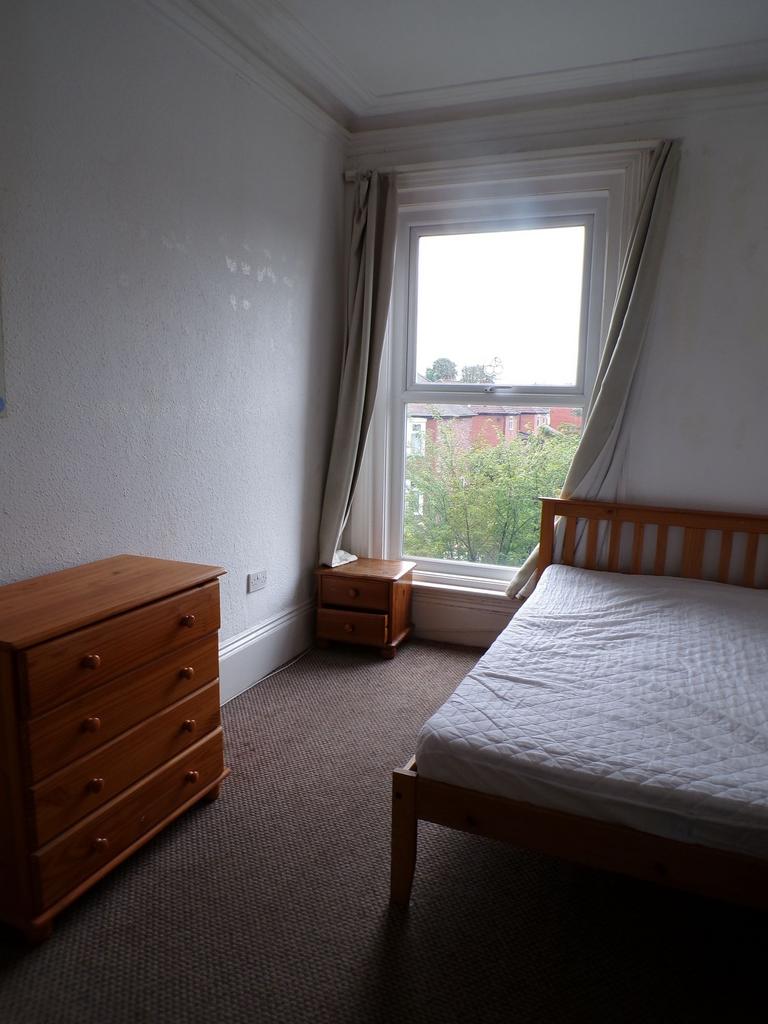 Bright bedroom with a large sash window and neu...