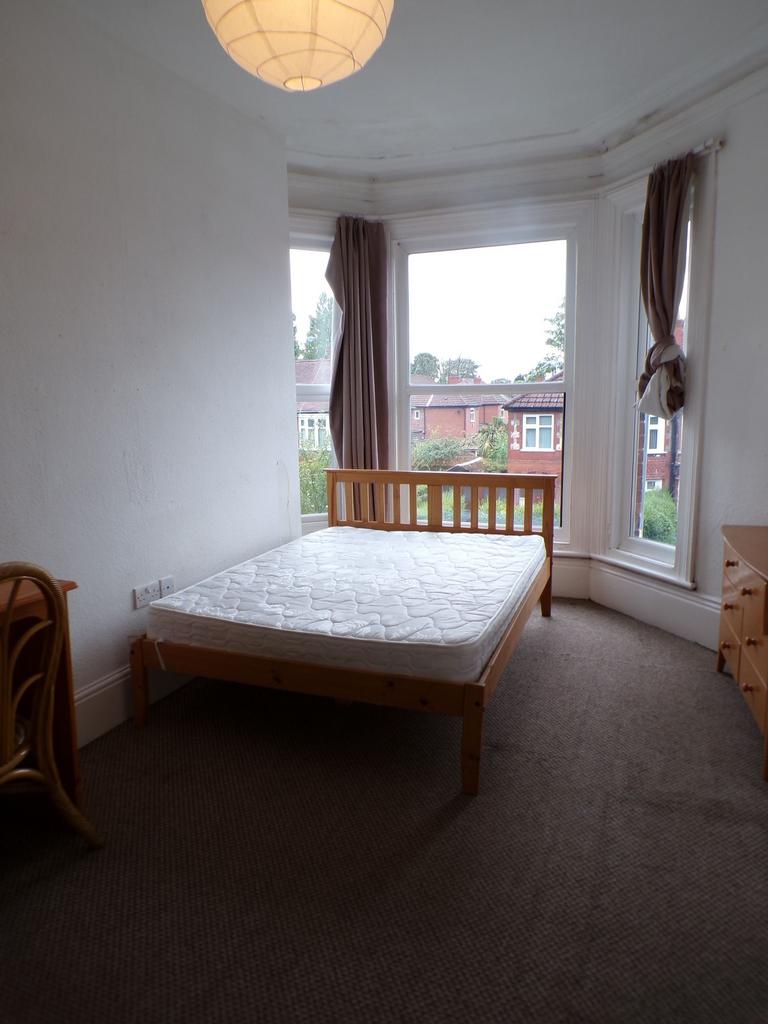 Bright double bedroom with a wooden bed frame p...