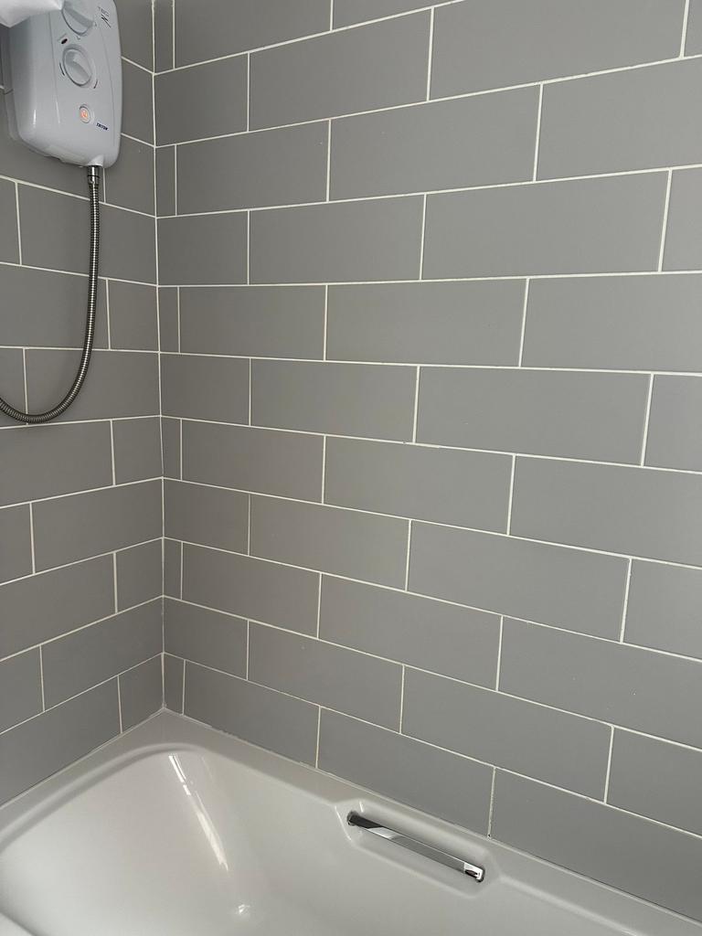 Modern bathroom featuring sleek grey tiled wall...