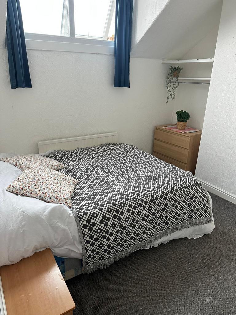 A cozy double bedroom with a comfortable bed dr...