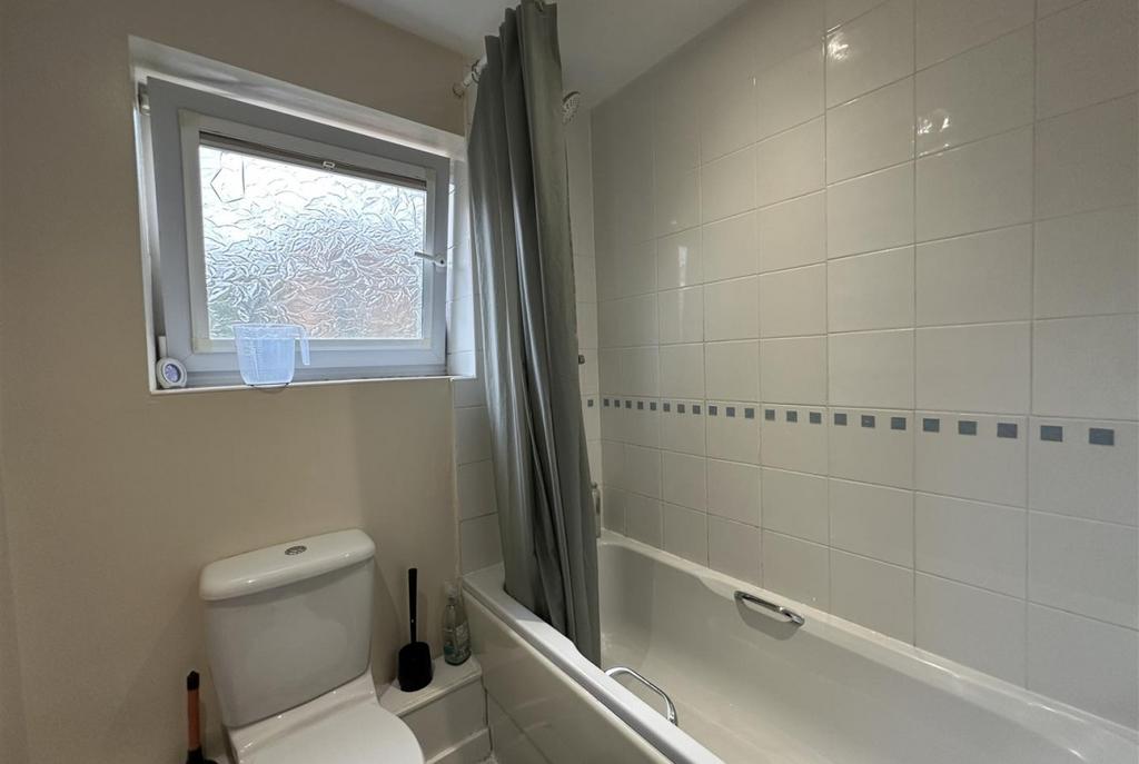 Bright, well-kept bathroom with a white tiled b...