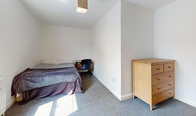 Bright, simply furnished bedroom with a double ...