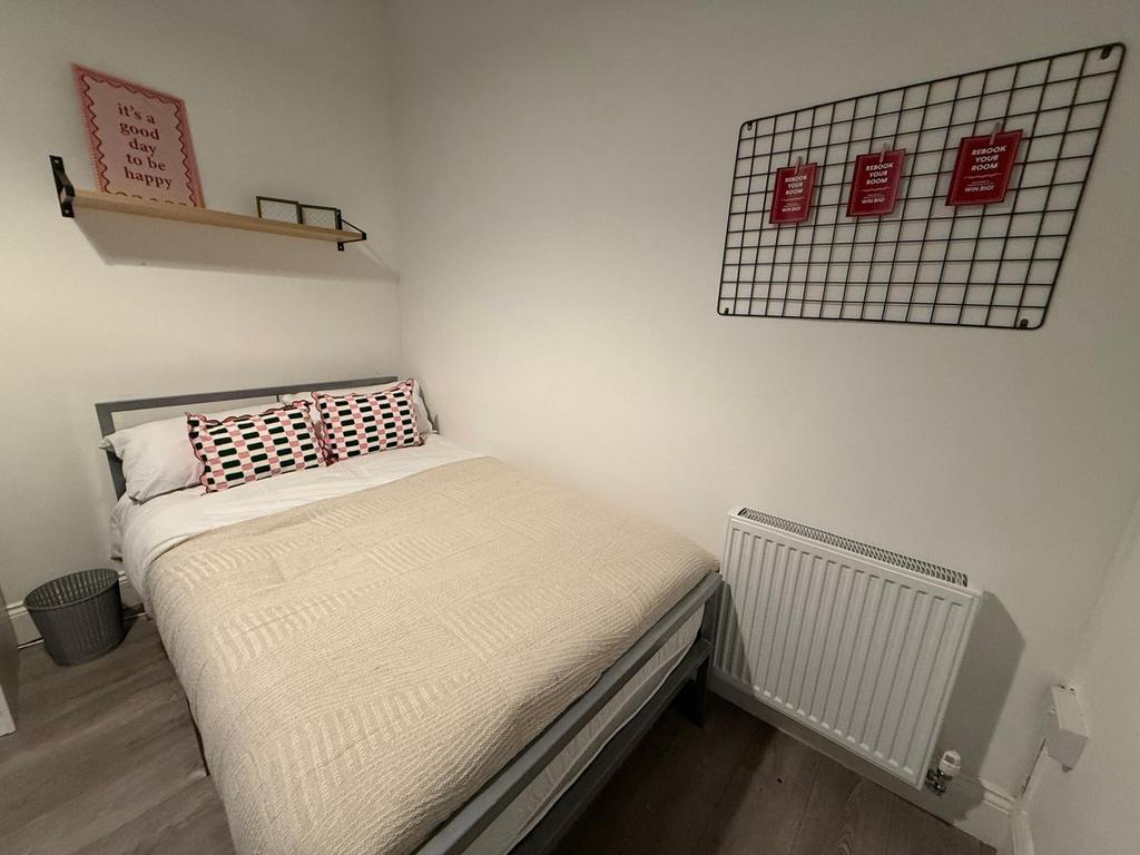 Cozy double bedroom with a neatly made bed, neu...