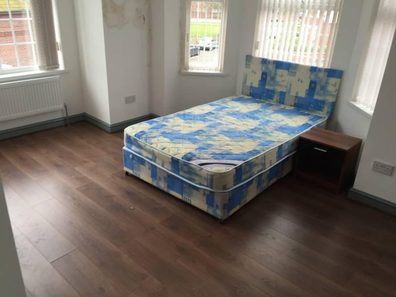 Bright corner double bedroom with three tall wi...