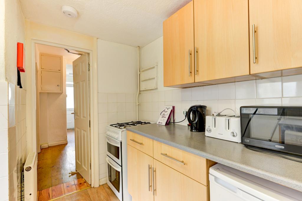 Neat galley kitchen with light wood cabinets, t...