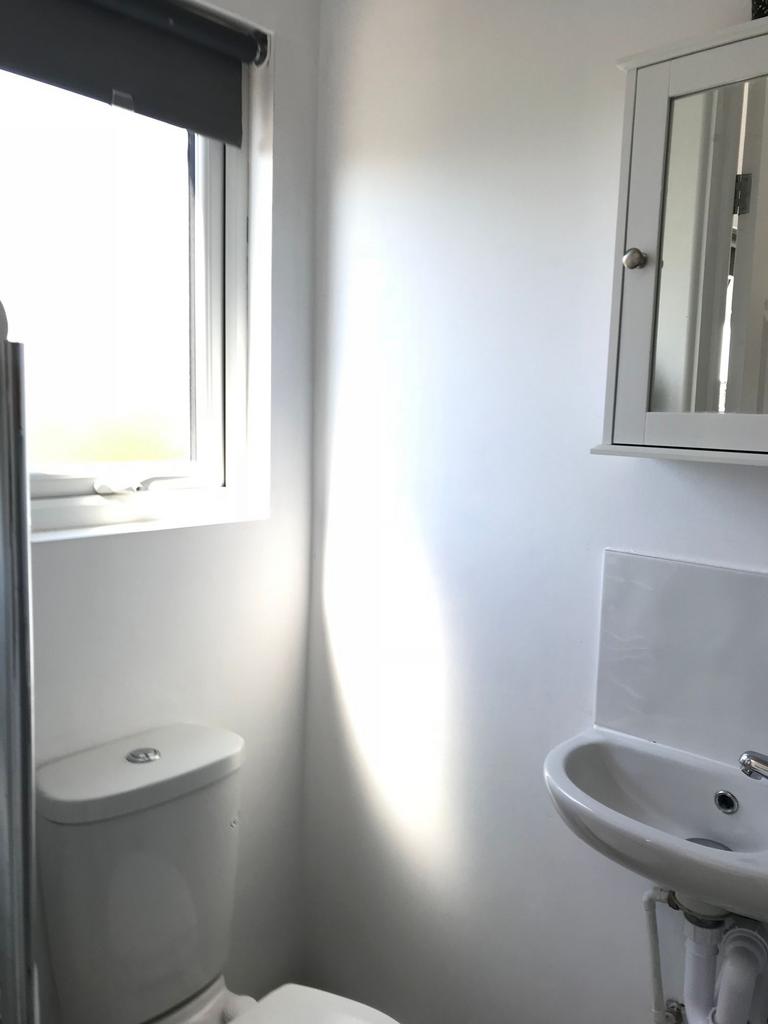 Bright, freshly painted small bathroom with a m...