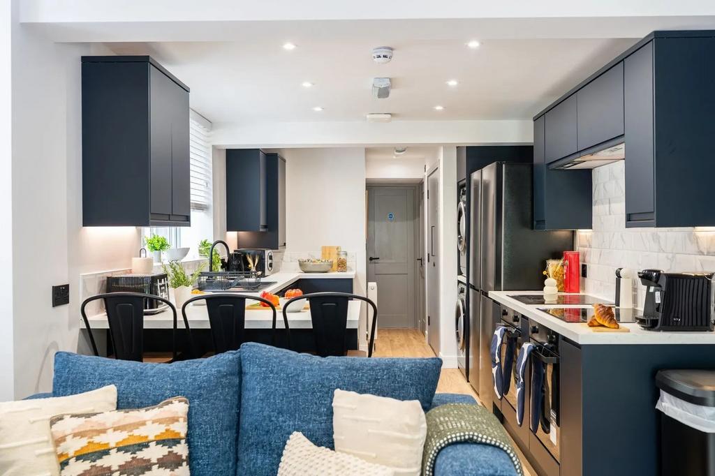 Modern open-plan kitchen with dark cabinetry, b...