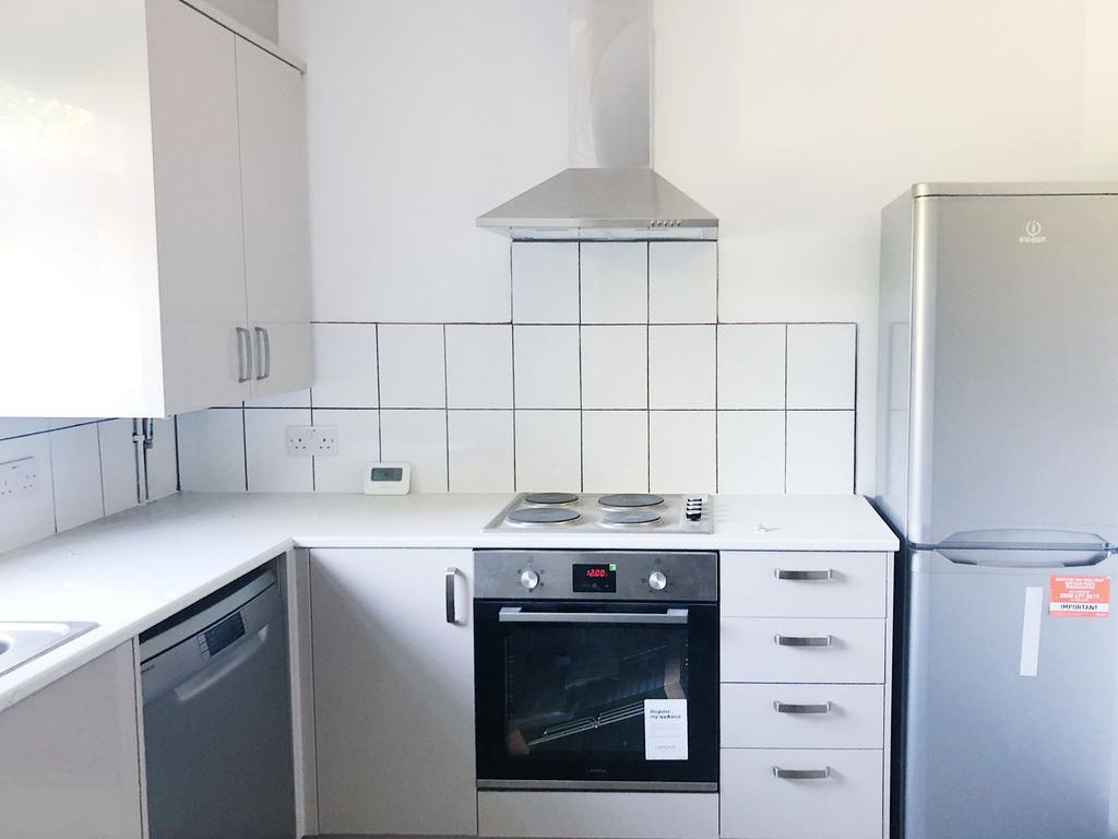 Bright, modern kitchen with white cabinets, ele...
