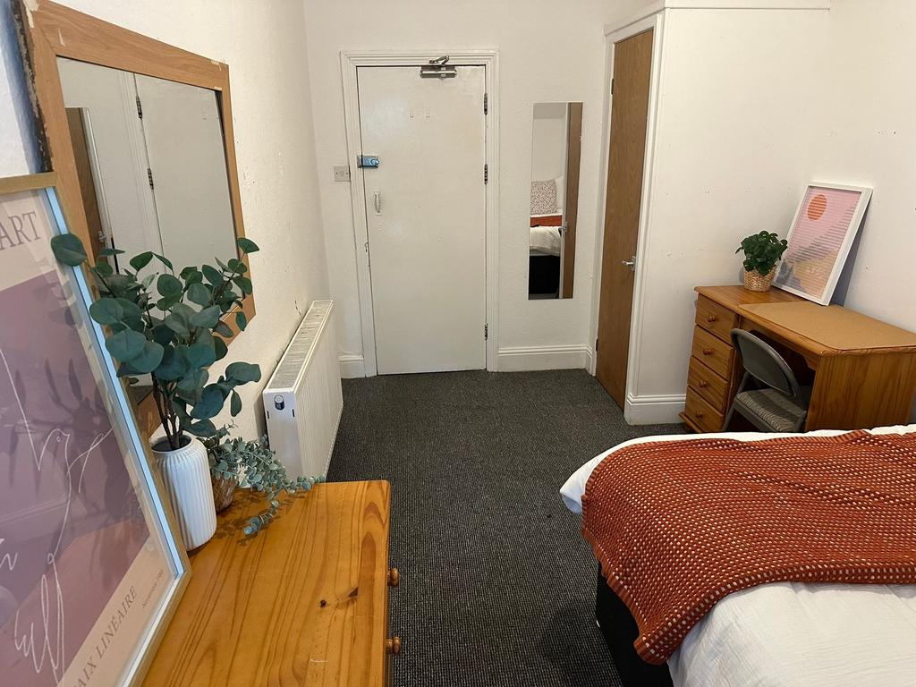 A cozy bedroom featuring a neatly made bed with...