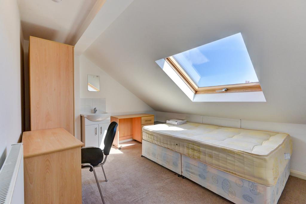 A bright and cozy bedroom featuring a sloped ce...