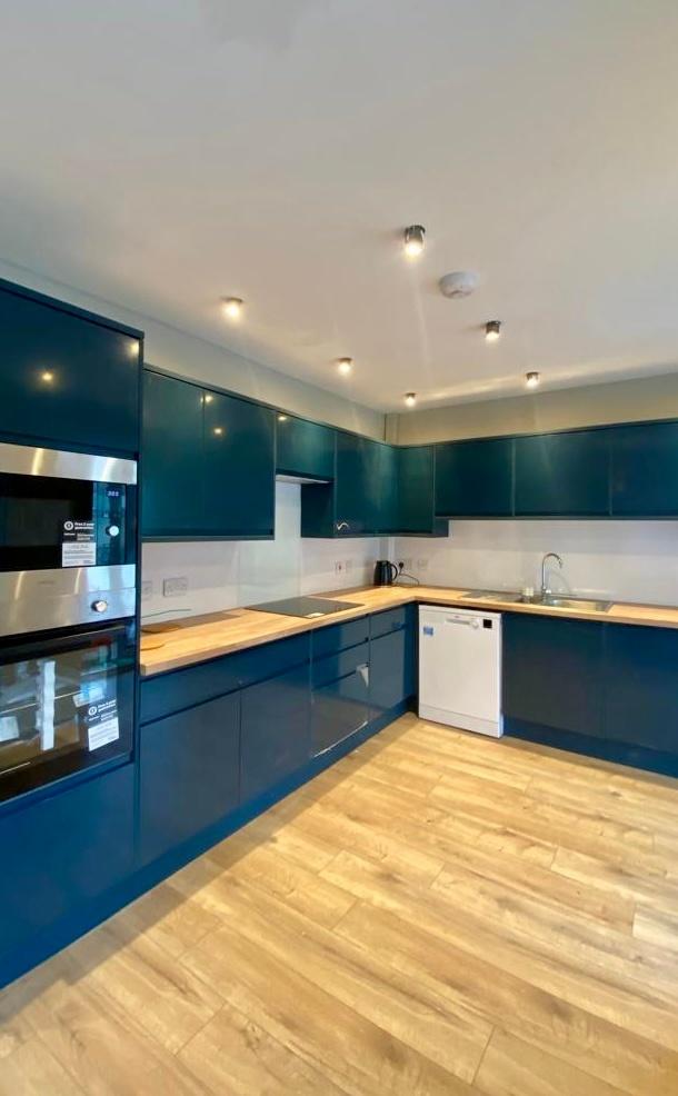 Modern kitchen featuring sleek dark blue cabine...