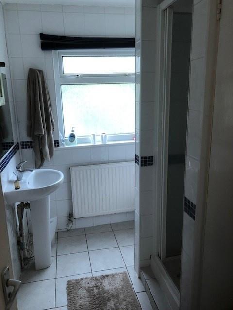 Bright white-tiled bathroom with a pedestal was...