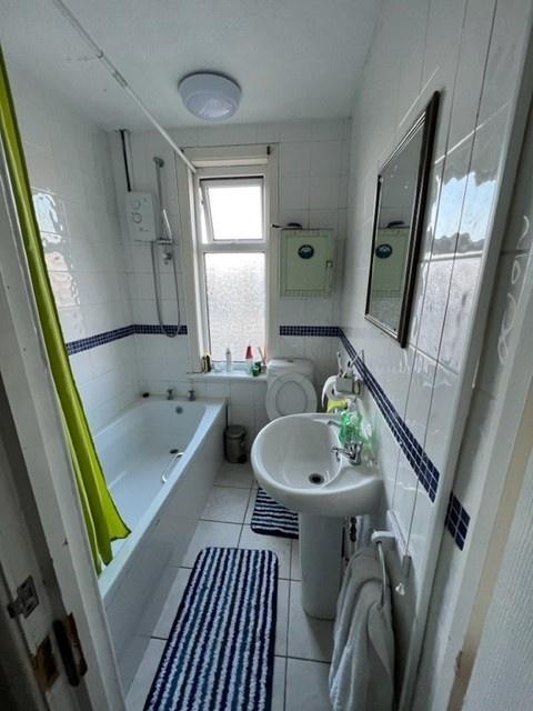 Bright tiled bathroom with a bathtub, pedestal ...
