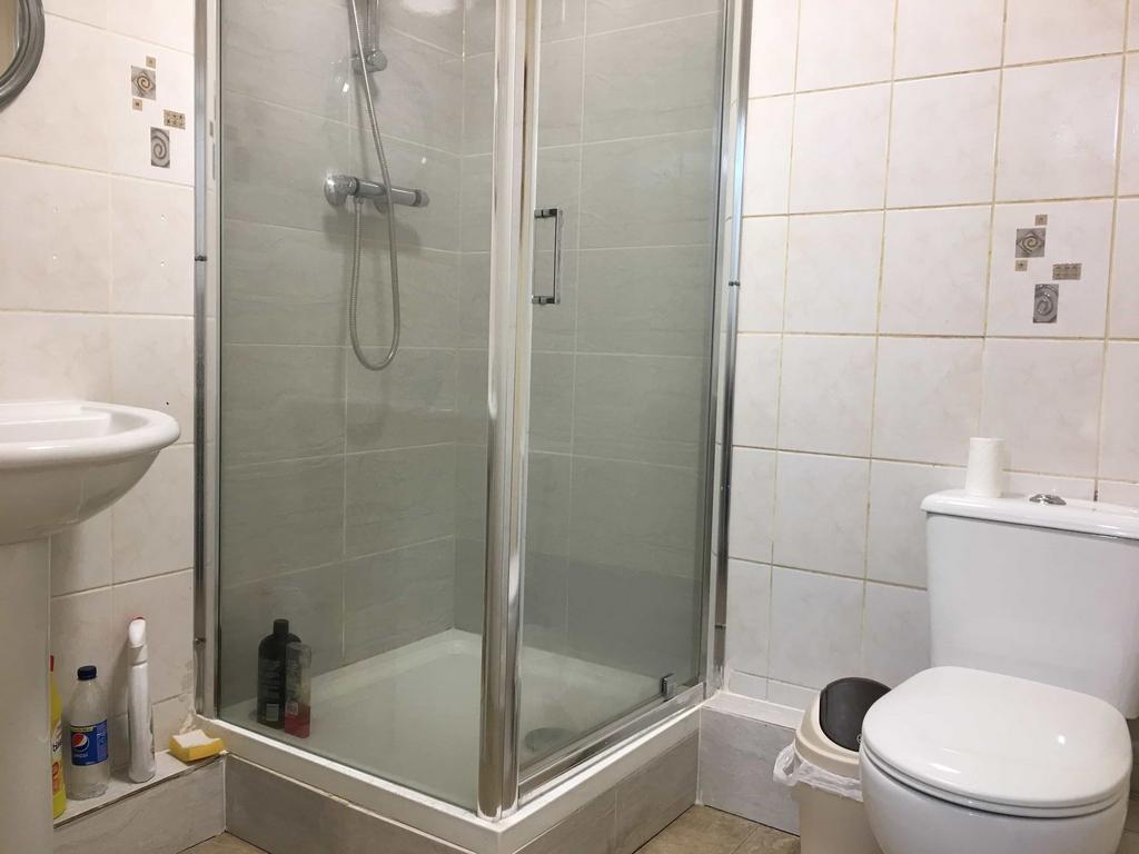 Bright tiled bathroom with a corner glass showe...