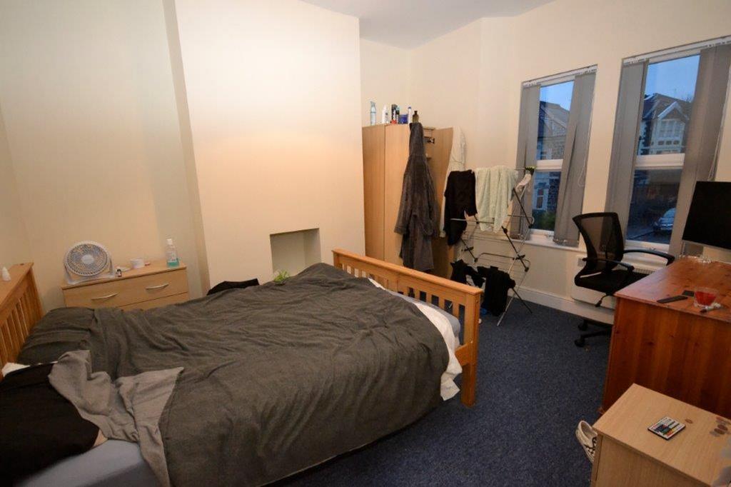 A tidy double bedroom with a bed, desk, and nat...