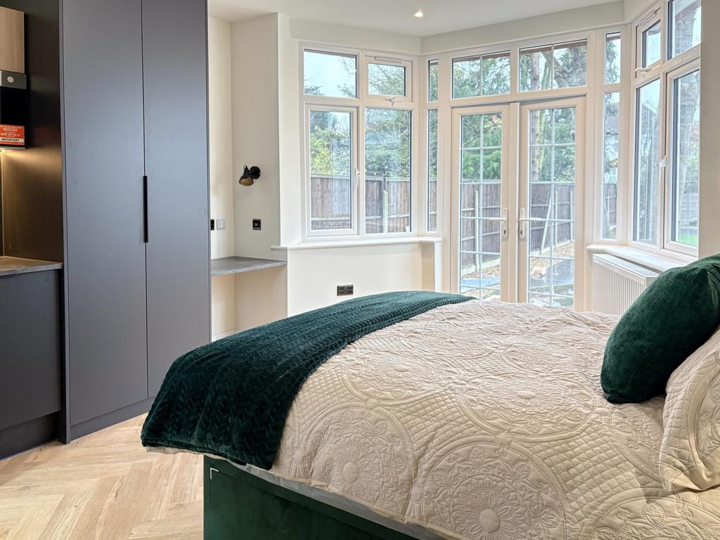 Bright, modern master bedroom with large bay wi...