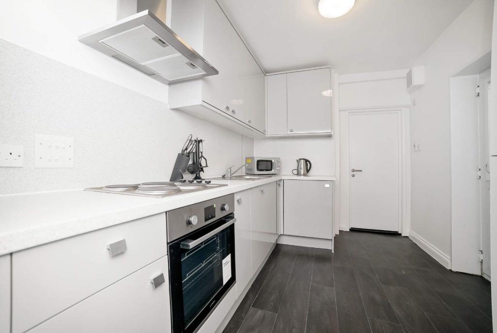 Bright modern galley kitchen with integrated ov...
