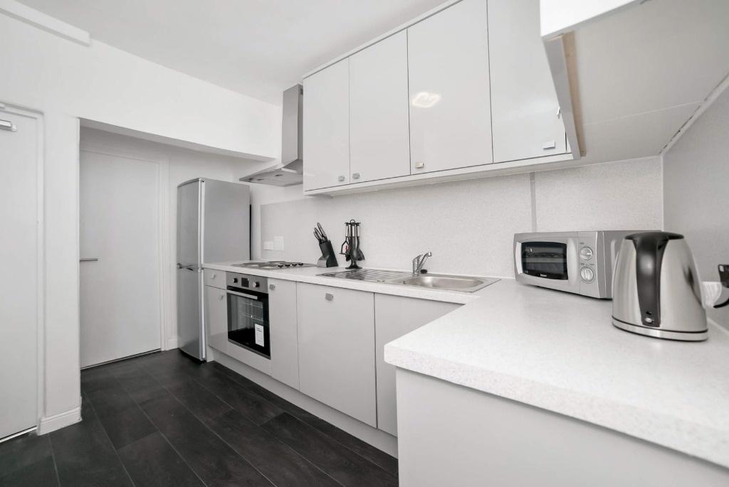 Bright, modern kitchen with integrated oven and...