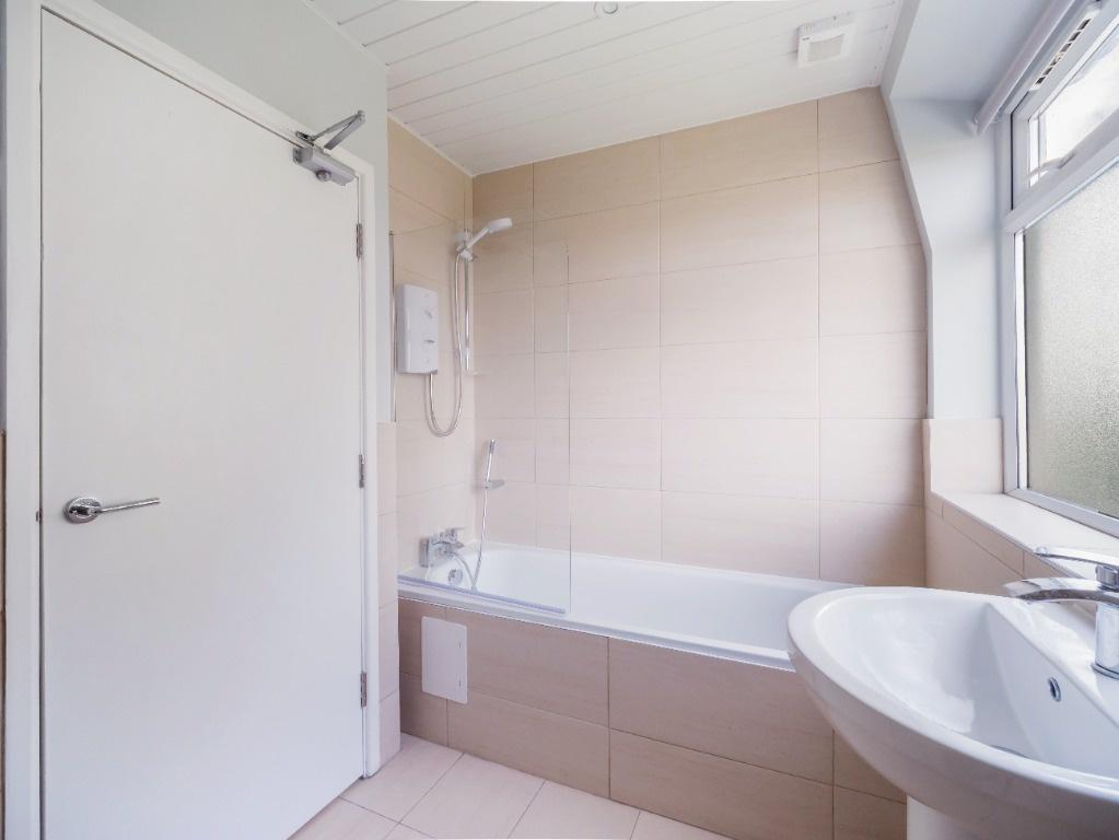 Bright, modern bathroom with a tiled bath and f...