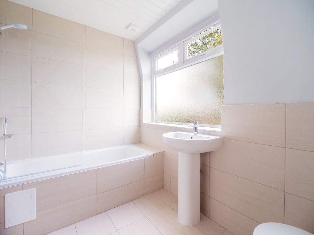Bright, modern bathroom with a tiled bath and a...